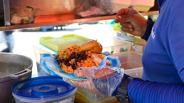 Un almuerzo con pollo cuesta $5.300. Es servido en un plato plástico que va cubierto por una bolsa plástica.