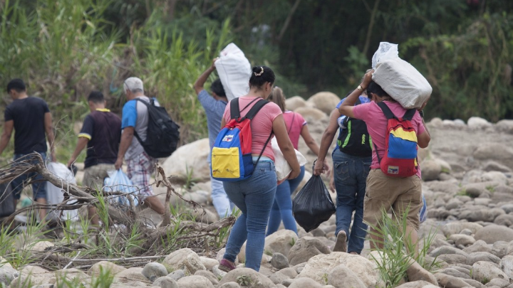 Venezolanos pasan con maercancías por río Táchira.