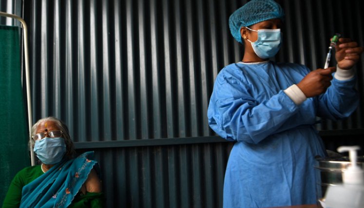 Un trabajador de la salud se prepara para vacunar a una mujer contra el coronavirus COVID-19 en las afueras de Katmandú.