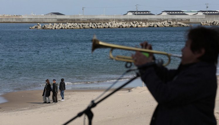 Un residente local toca una trompeta para las víctimas del terremoto y tsunami en una playa en Soma el 11 de marzo de 2021, el décimo aniversario del terremoto de magnitud 9.0 que provocó un tsunami y un desastre nuclear. / Foto: AFP