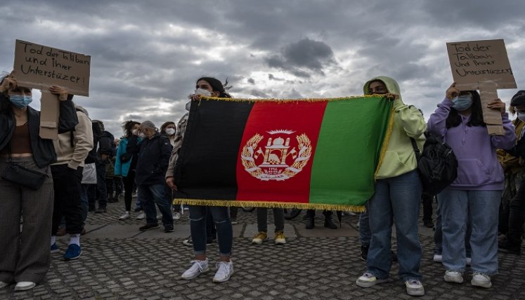Mujeres muestran una bandera afgana mientras se manifiestan frente al edificio del Reichstag, sede de la cámara baja del parlamento Bundestag, en Berlín, para exigir un paso seguro para los afganos amenazados por los talibanes./ Foto AFP