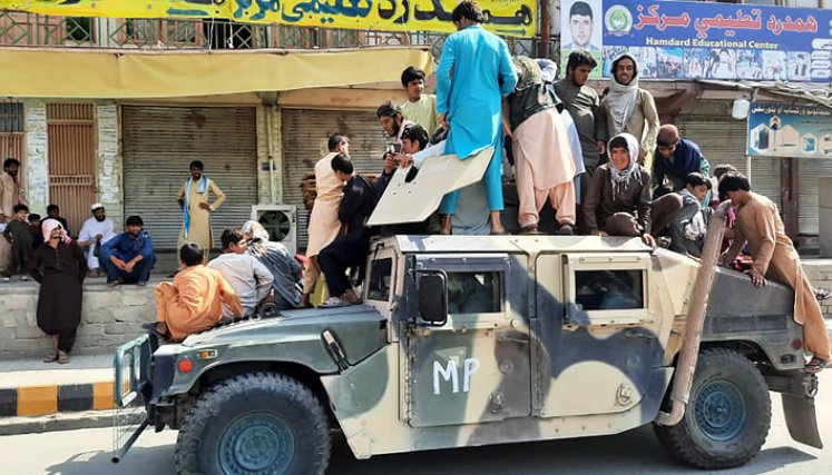 Los combatientes talibanes y los residentes locales se sientan sobre un vehículo Humvee del Ejército Nacional Afgano (ANA) a lo largo de la carretera en la provincia de Laghman el 15 de agosto de 2021. / Foto: AFP