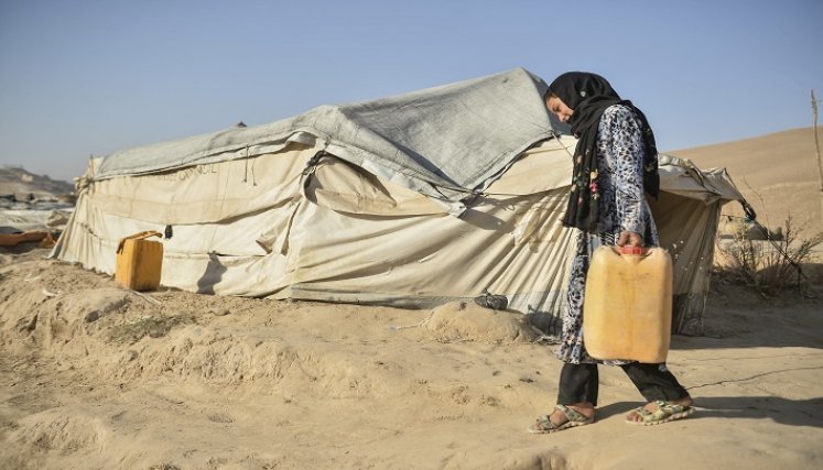 Una niña que vive con su madre pero que debería haber ido a reunirse con la familia de su futuro cónyuge hace un mes, cargando un bidón lleno de agua. / AFP