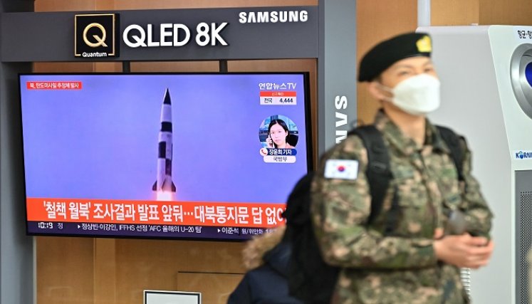 Un soldado surcoreano pasa junto a una pantalla de noticias de televisión que muestra imágenes de una prueba de misiles norcoreanos, en una estación de tren en Seúl ./ AFP