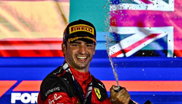 El piloto español de Ferrari Carlos Sainz Jr celebrá con champán desde el podio su victoria en el GP de Singapur de F1, el 17 de septiembre de 2023. Foto: Lillian SUWANRUMPHA / AFP