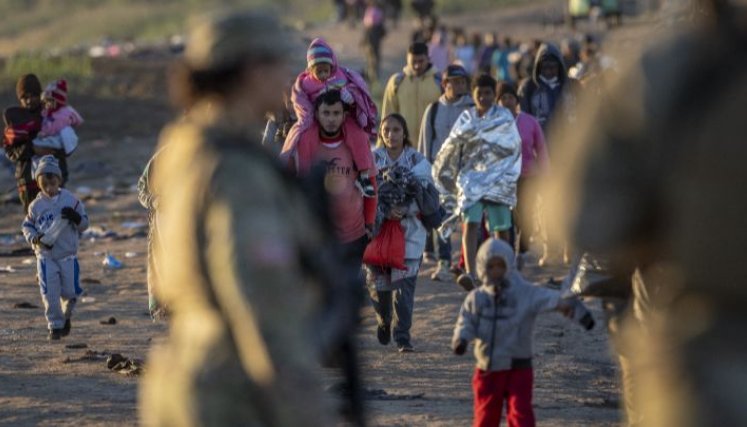 Estados Unidos-Soldados de la Guardia Nacional de Texas observan cómo miles de migrantes caminan hacia un centro de tránsito de la Patrulla Fronteriza de EE. UU. el 19 de diciembre en Eagle Pass.