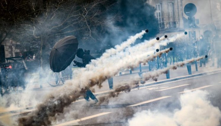 Francia-Un ciudadano sostiene un paraguas para protegerse de los gases lacrimógenos, durante las manifestaciones en Nantes contra la reforma de las pensiones propuesta por el gobierno, el 15 de marzo.