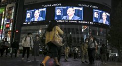 Peatones en calle ven una transmisión de televisión del primer ministro de Japón, Yoshihide Suga, anunciando el levantamiento del estado de emergencia por coronavirus./ AFP 