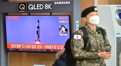 Un soldado surcoreano pasa junto a una pantalla de noticias de televisión que muestra imágenes de una prueba de misiles norcoreanos, en una estación de tren en Seúl ./ AFP