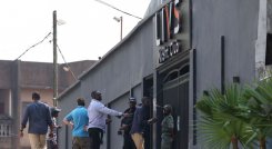 Transeúntes pasan junto a los policías que hacen guardia en la entrada del club nocturno Livs, donde se produjo un incendio mortal en el distrito de Bastos de Yaundé. / Foto: AFP