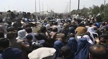 Los afganos se reúnen al borde de la carretera cerca de la parte militar del aeropuerto de Kabul, con la esperanza de huir del país después de la toma militar por los talibanes. / AFP