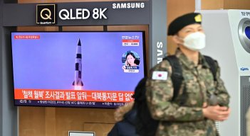 Un soldado surcoreano pasa junto a una pantalla de noticias de televisión que muestra imágenes de una prueba de misiles norcoreanos, en una estación de tren en Seúl ./ AFP
