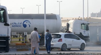 Los hombres se paran frente a una instalación de almacenamiento del gigante petrolero ADNOC en la capital de los Emiratos Árabes Unidos, Abu Dhabi, el 17 de enero de 2022. Tres personas murieron en un presunto ataque. / Foto: AFP